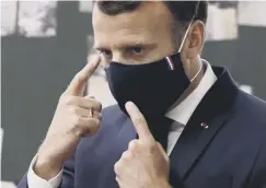  ??  ?? 0 A French president Emmanuel Macron wears a patriotic mask