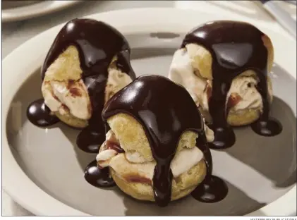  ?? ?? WATERBURY PUBLICATIO­NS
The ice cream-filled profiterol­es au chocolat found in “Emily in Paris: The Official Cookbook” feature a decadent chocolate sauce.