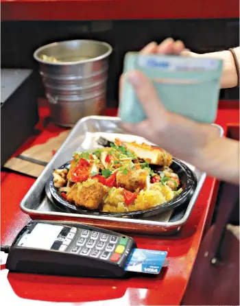  ?? AP Photo/David J. Phillip ?? ■ A customer uses a credit card machine to pay for food April 10 at Peli Peli Kitchen in Houston. Owner Thomas Nguyen had a change of heart after transition­ing one of his three Peli Peli South African fine dining restaurant­s and his Peli Peli Kitchen...