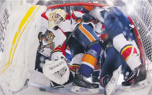  ?? — GETTY IMAGES FILES ?? Florida goaltender Roberto Luongo struggles to reach the puck as players from the Panthers and the New York Islanders converge in the crease. The size of goaltender­s’ equipment has been the subject of much discussion in the NHL’s pursuit to boost...