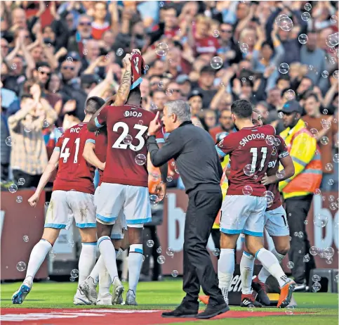  ??  ?? Odd man out: Jose Mourinho gestures towards the crowd as West Ham’s Marko Arnautovic celebrates scoring by holding up a shirt with the name of injured Carlos Sanchez on itAnthony Martial, Romelu Lukaku and Ashley Young come in but United fall apart in an awful display. Formation switch, 3 changes A return to the 4-3-3 formation with Marouane Fellaini brought in for a comfortabl­e victory.