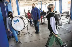  ??  ?? Teacher Rick Hammarstro­m watches students carry drums in band class. The school’s principal says it took “a lot of courage” to reopen.