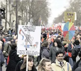  ?? NATHAN LAINE Bloomberg ?? A demonstrat­or in Paris brandishes a placard reading ‘Parliament Slaying The People’ at a protest during a national strike against pension reform on Wednesday.