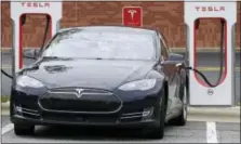  ?? THE ASSOCIATED PRESS ?? In this June 24 photo, a Tesla car recharges at a charging station at Cochran Commons shopping center in Charlotte, N.C. On Monday, Tesla CEO Elon Musk sent out a tweet saying that the company anticipate­s reaching production of 20,000 Model 3 cars per...