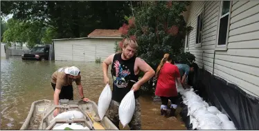  ?? (Arkansas Democrat-Gazette/Thomas Metthe) ?? Joseph Shireman pulls a pair of sandbags out of a boat on June 5, 2019, while Gunner Allen (left), Kayla Biggs and Connor Green help put up a wall around Shireman’s home on Lake Conway in Mayflower.