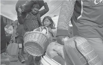  ?? AP Photo/Gregory Bull ?? ■ Brittany Rios of Honduras, center, carries stuffed animals in a wicker basket as her family leaves a shelter for members of the Central American migrant caravan Friday in Tijuana, Mexico.