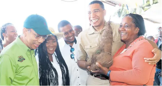  ??  ?? Prime Minister Andrew Holness (second right) congratula­tes yam farmer Althea Pryce in Trelawny, along with Agricultur­e Minister Floyd Green (centre), Horace Chang (left) and newly elected Member of Parliament for Trelawny Northern, Tova Hamilton.