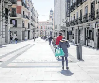  ?? FOTO: RICARDO RUBIO/DPA ?? Menschen stehen vor einem Supermarkt in der sonst leergefegt­en Innenstadt von Madrid Schlange.