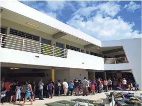  ?? CARLOS GIUSTI/AP ?? People whose homes are unsafe to enter after the previous day's magnitude 6.4 earthquake line up for lunch in an outdoor area of the Bernardino Cordero Bernard High School, which is being used as a shelter despite no electricit­y in Ponce, Puerto Rico, on Jan. 8. Puerto Rico opened only 20% of its public schools Tuesday following a strong earthquake that delayed the start of classes by nearly three weeks as fears linger over the safety of students.