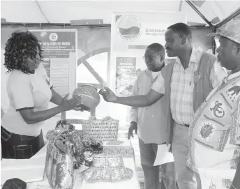  ??  ?? Umzingwane District Administra­tor Mr Bekithemba Ndlovu gets a feel of a pot made of plastic on display at the Umzingwane District Agricultur­al Show which was held at Esigodini in Matabelela­nd South Province yesterday. Holding the plastic pot is the...