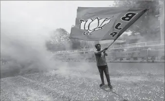  ?? -AP ?? A BJP supporter waves a party flag as he celebrates after learning the initial election results.