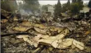  ?? BEN MARGOT — THE ASSOCIATED PRESS ?? Smoke raises from the remains of homes across the street from houses unscathed on Tuesday in the Coffey Park area of Santa Rosa.