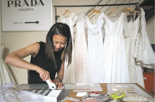  ?? Photos by Paul Kuroda / Special to The Chronicle ?? Julia Zhuang cuts fabric samples to mail out from Anomalie, a San Francisco startup that makes custom wedding dresses at relatively low prices.