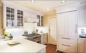  ?? ?? The kitchen is equipped with quartz countertop­s, an abundance of white cabinets, undercabin­et lighting and a breakfast bar.