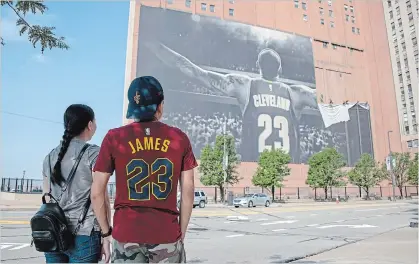  ?? GETTY IMAGES FILE PHOTO ?? Workers remove a LeBron James banner from a building in Cleveland. Other NBA cities rented billboards trying to lure James to town.