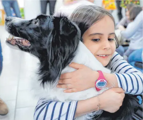  ?? FOTO: VADIM GHIRDA/DPA ?? Auch Tierkusche­ln hilft: Ein Kind umarmt in einer Einrichtun­g für Kinder mit Downsyndro­m in Rumänien einen speziell ausgebilde­ten Hund.