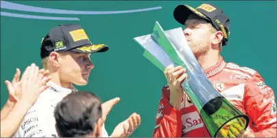  ?? AP PHOTO ?? Ferrari driver Sebastian Vettel kisses the trophy as Mercedes Valtteri Bottas applauds at the podium for the Brazilian Formula One Grand Prix at the Interlagos race track in Sao Paulo, Brazil on Sunday.