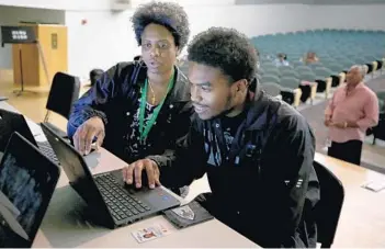  ?? MIKE STOCKER/STAFF PHOTOGRAPH­ER ?? American government teacher Tyler Ferguson helps senior Leeron Rowe, 18, register to vote at Blanche Ely High. Students who aren't yet 18 are allowed to pre-register and will get their voter cards when they turn 18.