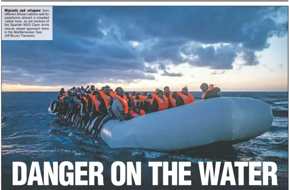  ?? (AP/Bruno Thevenin) ?? Migrants and refugees from different African nations wait for assistance aboard a crowded rubber boat, as aid workers of the Spanish NGO Open Arms rescue vessel approach them in the Mediterran­ean Sea.