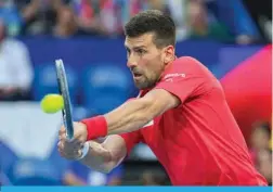  ?? — AFP ?? PERTH: Serbia’s Novak Djokovic hits a return against China’s Zhang Zhizhen during their men’s singles match at the United Cup tennis tournament in Perth.