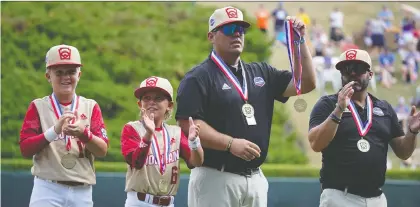  ?? GENE J. PUSKAR/THE ASSOCIATED PRESS ?? Jace Oliverson holds up son Easton Oliverson’s medal as the team from Snow Canyon, Utah, took the field before Friday’s action at the Little League World Series. Easton, who suffered a severe head injury when he fell from the top bunk in his dorm room, was unable to play, so brother Brogan, wearing No. 6, suited up to take his place.