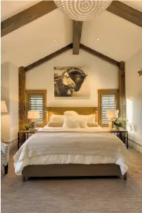  ??  ?? Top: A raised gas fireplace sits beneath an exposed beam ceiling and inside a stone mantle in a living room that opens to
a deck. Above left: Vaulted, beamed ceilings give the master suite a dramatic feel. Above right: Commercial-grade appliances,...