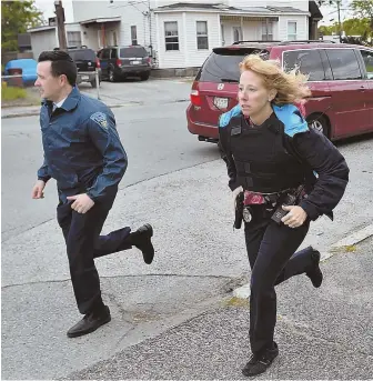  ?? STAFF PHOTOS, ABOVE AND TOP RIGHT, BY CHRISTOPHE­R EVANS; TOP LEFT, BY NICOLAUS CZARNECKI ?? ON THE RUN: Officers search the streets of Lowell for signs of 51-year-old suspect Ross Elliott, who is wanted in connection with the slaying of a 44-yearold woman. Officials say she had a ‘domestic relationsh­ip’ with Elliott.