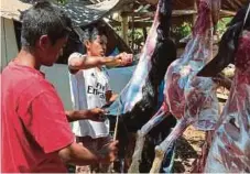  ??  ?? PENDUDUK tempatan membantu melapah daging kambing untuk dimasak dalam program kenduri rakyat.