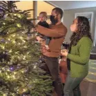  ?? PAULA BRONSTEIN/AP ?? Ani Sirois, right, decorates the Christmas tree with daughter Ida, 2, and husband, Chadwick, at their home on Tuesday in Portland, Ore.