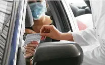  ?? Elizabeth Conley / Staff photograph­er ?? Nurse practition­er Hai Dong hands off a COVID-19 vaccinatio­n card at a drive-thru site earlier this year.