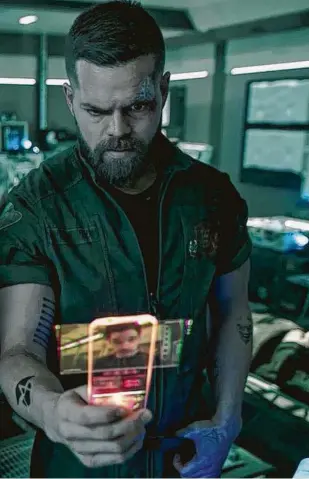  ?? Amazon Prime Video ?? Wes Chatham, as Amos Burton, studies a hand terminal in “The Expanse,” the hit sci-fi series on Amazon Prime Video.