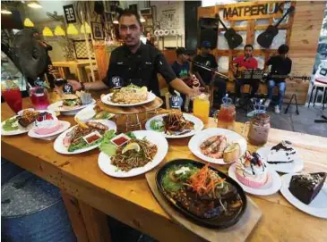  ??  ?? Mohd Rani bersama hidangan popular di Mat Periuk Cafe, Ipoh.