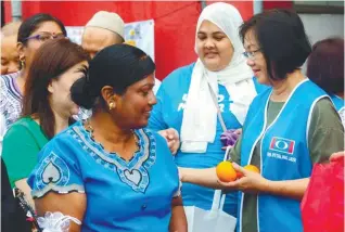  ??  ?? Maria handing gifts at Petaling Jaya Old Town market yesterday in conjunctio­n with Mother's Day.