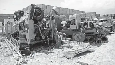  ?? RAHMAT GUL/AP ?? A man rests in the shade of destroyed machinery sold by the U.S. military to a scrapyard May 3 outside Bagram Airfield in Afghanista­n. In 2001, Bagram was chosen as the epicenter of Operation Enduring Freedom.