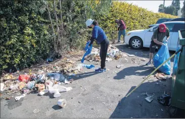  ?? PHOTOS BY CHUCK BENNETT ?? Torrance Little League parents and kids clean the street outside the ball field in their annual cleanup of the neglected road on the eastern edge of Torrance that suffers from illegal dumping, littering and other illicit activities on the one-way street.