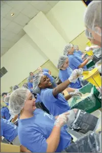  ?? The Sentinel-Record/Grace Brown ?? PACK IT UP: Grace Rooney, left, of Guy, and Halli Lemons, of Newport, work to pack 30,000 meals with other members of the Arkansas Future Farmers of America Wednesday at Camp Couchdale.