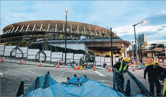  ?? PHILIP FONG / AFP ?? Un grupo de trabajador­es seguía acondicion­ando los aledaños del estadio Nacional de Tokio el pasado viernes