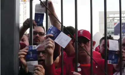 ?? Photograph: Christophe Ena/AP ?? Liverpool fans display their tickets for last May’s Champions League final outside the Stade de France.