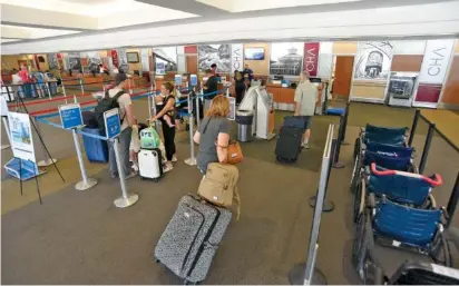  ?? STAFF PHOTO BY MATT HAMILTON ?? Passengers line up June 21 to check their luggage at Chattanoog­a Airport. Boardings there up nearly 15% in 2022 over 2021.