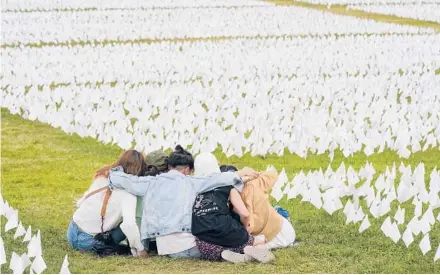  ?? PATRICK SEMANSKY/AP ?? Visitors sit among white flags Sept. 21 that are part of“In America: Remember”in Washington.