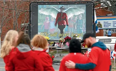  ?? AP ?? Mourners, asked to wear red yesterday, are seen by a mural dedicated to slain Royal Canadian Mounted Police Constable Heidi Stevenson, during a province-wide, two-minutes of silence for the 22 victims of last weekend’s shooting rampage, in front of the RCMP detachment in Cole Harbour, Nova Scotia.