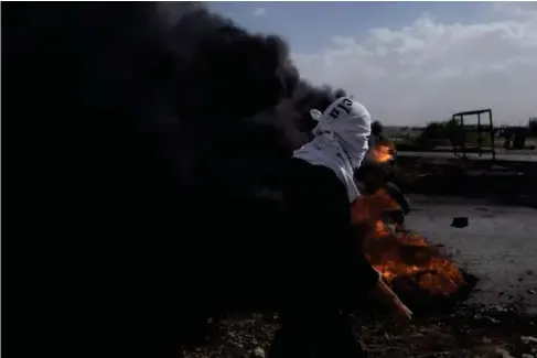  ?? (AP) ?? Pa l estinian protesters b l ock a road with burning tires in the West Bank after the Israe l i army ki lls five gunmen