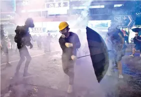  ?? Photo: AFP ?? Protesters try to avoid tear gas let off by riot Police in Hong Kong.