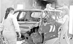  ?? — AFP photo ?? Employees work on the assembly line of the Peugeot 208 car by French car maker PSA Peugeot Citroen at the company’s automobile factory in Trnava, western Slovakia. Slovakia, the world’s largest per capita car producer, stands to be hardest hit if US...