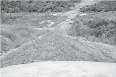  ??  ?? Vehicles stop by the roadside to give way as oncoming vehicles struggle to negotiate the slippery mud track.