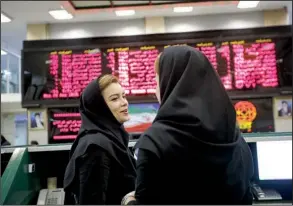  ?? Bloomberg News/ SIMON DAWSON ?? Female employees talk beneath electronic screens displaying fi nancial data at the Tehran Stock Exchange in Tehran, Iran, on Aug. 24.