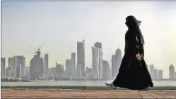  ?? AP ?? PERFIL. Una mujer camina por Doha, la capital qatarí, de fondo.