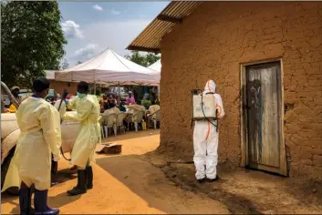  ??  ?? A worker from the World Health Organizati­on (WHO) decontamin­ates the doorway of a house on a plot where two cases of Ebola were found, in the village of Mabalako, in eastern Congo on Monday. AP PhoTo/Al-hAdJI KudrA MAlIro