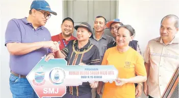  ?? ?? Joniston handing over the SMJ house key to Waitin Banggang of Kampung Ranau-Ranau.