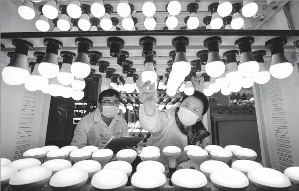  ?? WANG ZHENG / FOR CHINA DAILY ?? Technician­s check the quality of products for export at a bulb making factory in Huzhou, Zhejiang province, on Sunday .